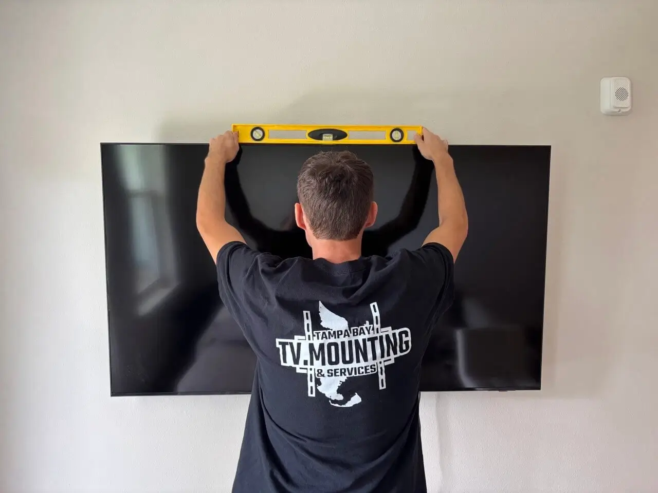 Professional TV installer mounting a television on the wall